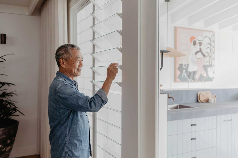 Homeowner adjusting glass louvre windows